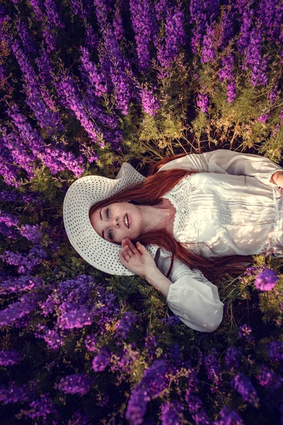 Hermosa mujer sobre fondo púrpura. mujer con flores púrpuras — Foto de Stock