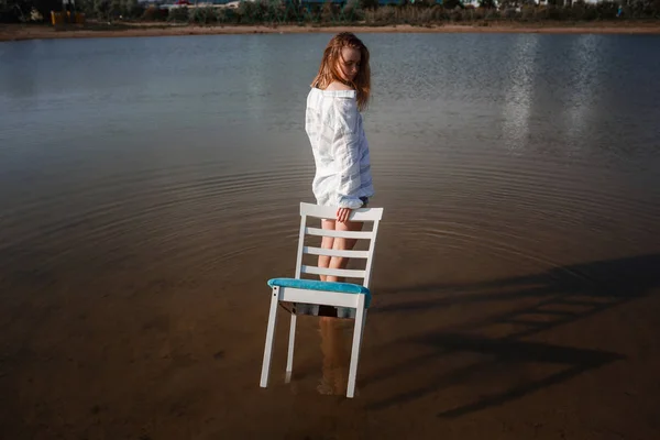 Uma linda adolescente em uma cadeira no meio de uma lagoa . — Fotografia de Stock