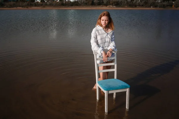 Een prachtige tienermeisje in een stoel in het midden van een vijver. — Stockfoto