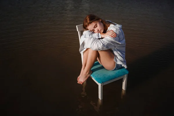 Una hermosa adolescente en una silla en medio de un estanque . — Foto de Stock