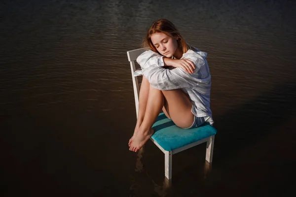 Una hermosa adolescente en una silla en medio de un estanque . — Foto de Stock