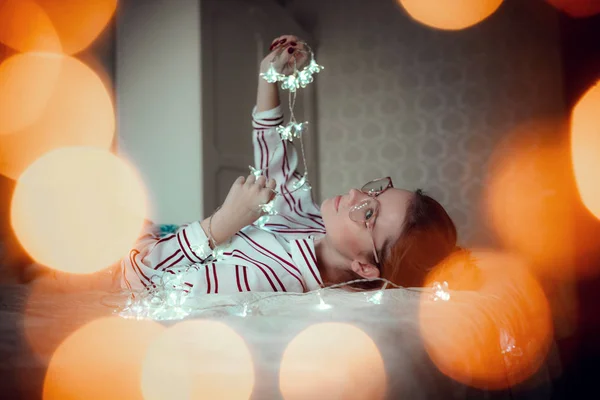 Jeune femme avec des lumières de fées rêvant au lit — Photo