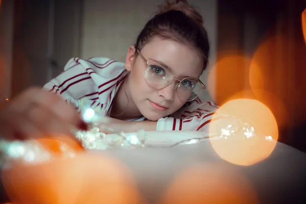 Young woman with fairy lights dreaming in bed — Stock Photo, Image