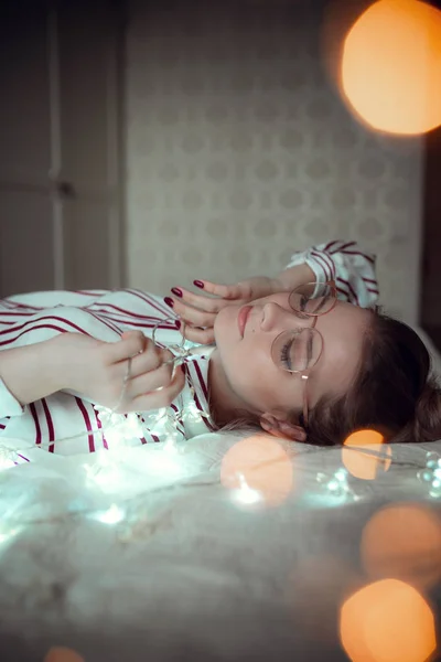 Jonge vrouw met fairy lichten dromen in bed — Stockfoto