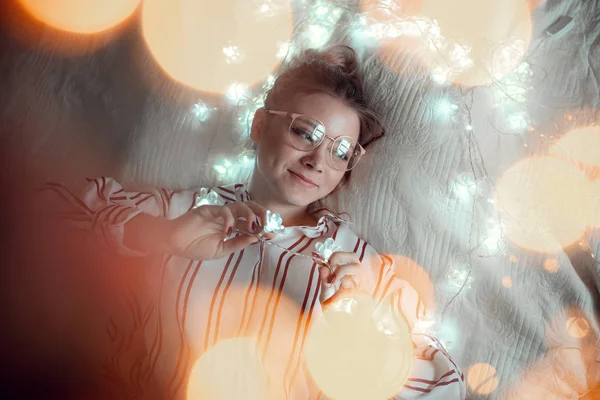 Mujer joven con luces de hadas soñando en la cama —  Fotos de Stock