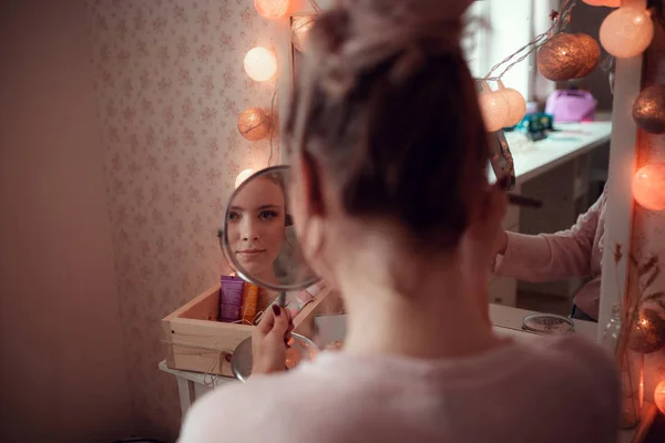 Linda chica se mira en el espejo, sala de luz . — Foto de Stock