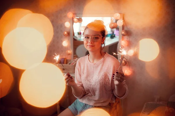 Blithesome young woman in sweater holding sparklers. — Stock Photo, Image