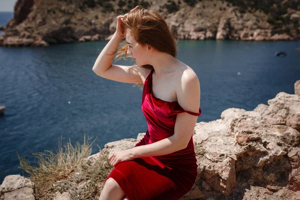 Una bella donna dai capelli rossi è seduta su una roccia — Foto Stock