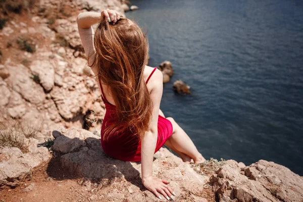 Una hermosa mujer pelirroja está sentada en una roca — Foto de Stock