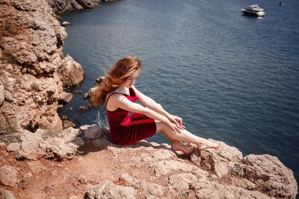 Eine schöne rothaarige Frau sitzt auf einem Felsen — Stockfoto