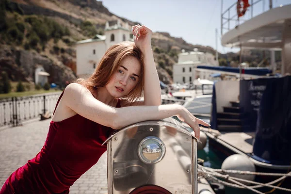 Bella donna dai capelli rossi in posa in porto nella soleggiata giornata estiva . — Foto Stock
