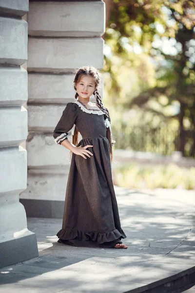Krásná holčička ve starých šatech na pozadí architektury historického centra — Stock fotografie