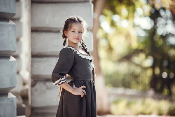 Bella bambina in un vecchio abito sullo sfondo dell'architettura del centro storico — Foto Stock