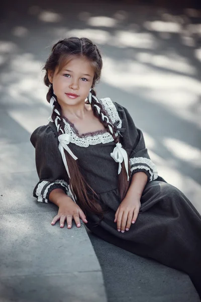 Красивая маленькая девочка в старом платье на фоне архитектуры исторического центра — стоковое фото