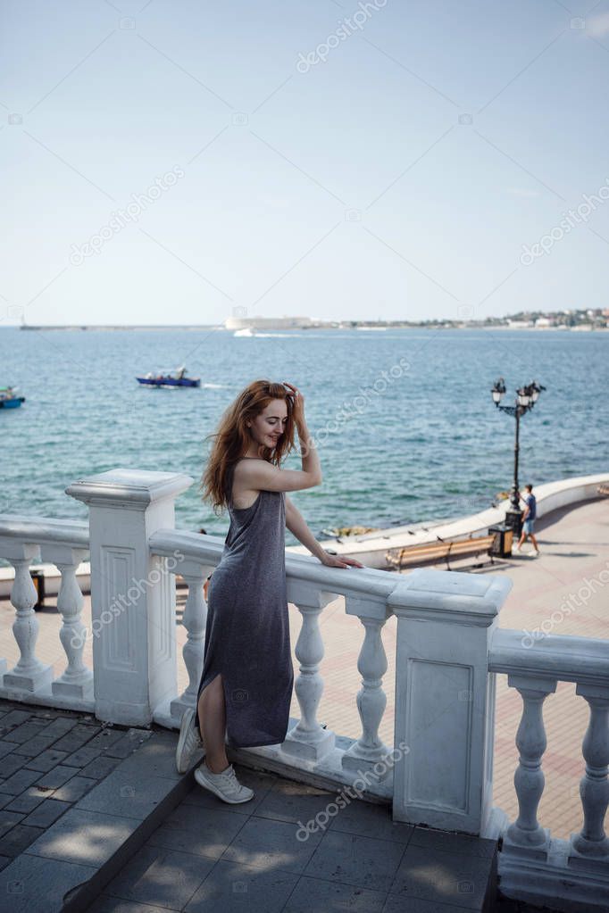 Portrait of elegant gorgeous young redhair woman wearing fashionable long coat on the city street