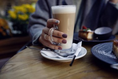 Genç güzel kız gülümseyen ve sokak açık kafede kahve içiyor. Kentsel sabah sahnesi