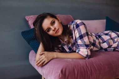 İç çamaşırı. Gülümseyen sevimli kız koltukta yalan poz