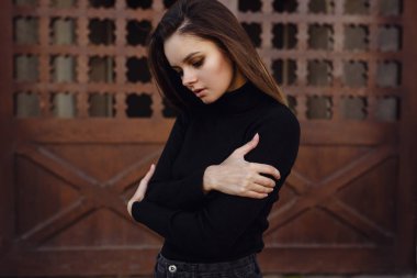 Güzel bir genç esmer siyah bir kazak ve ceket sonbahar Parkı boyunca yürür,