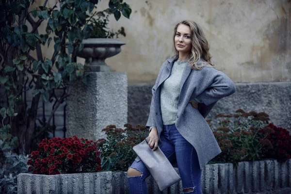 Fashion model dragen geripte vriendje jeans, jas en sneakers poseren in de stad — Stockfoto