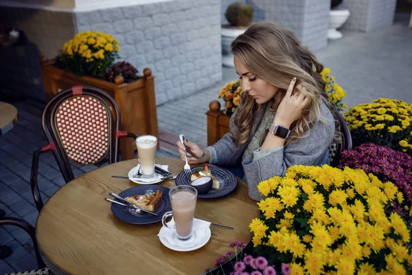 Jong mooi meisje glimlachen en het drinken van koffie in de straat outdoor cafe. Urban Morning scene — Stockfoto