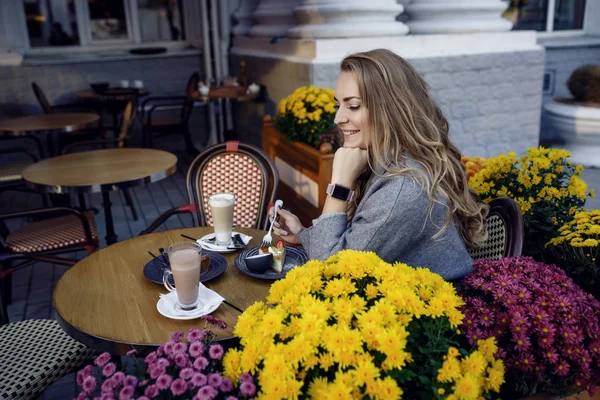 年轻美丽的女孩微笑着, 喝着咖啡在街头户外咖啡馆。都市早晨场面 — 图库照片