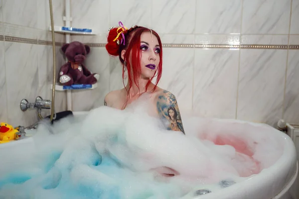 Modell wie eine Puppe mit Farbhörer liegt im Badezimmer, in der Badewanne. — Stockfoto