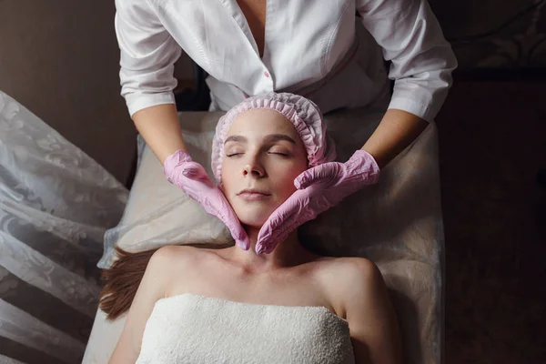 Kosmetologia pokój, kosmetyczka sprawia, że masaż twarzy młodej pięknej dziewczyny — Zdjęcie stockowe