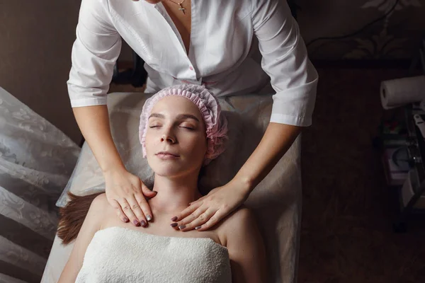 Cosmetology room, beautician makes facial massage to a young beautiful girl — Stock Photo, Image