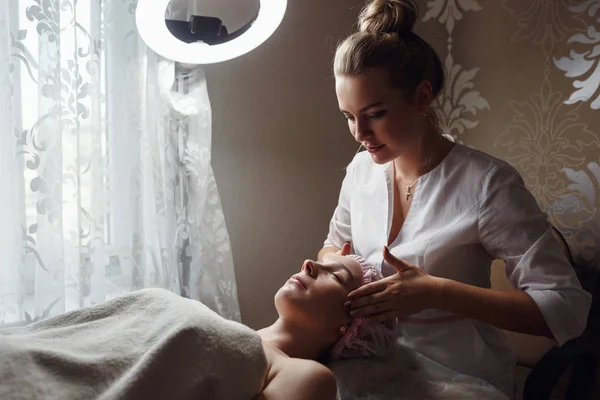 Kosmetologia pokój, kosmetyczka sprawia, że masaż twarzy młodej pięknej dziewczyny — Zdjęcie stockowe