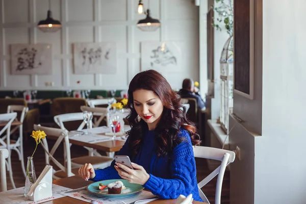 De vrouw in het café zit aan een tafel, drinkt koffie en kijkt naar Window — Stockfoto