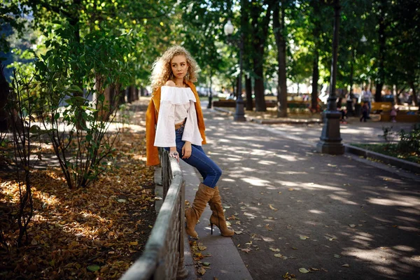 En vacker ung kvinna med blont lockigt hår går genom den soliga staden — Stockfoto