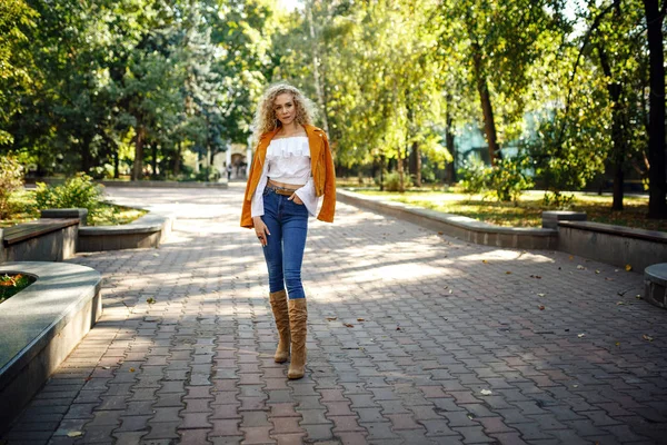 En vacker ung kvinna med blont lockigt hår går genom den soliga staden — Stockfoto