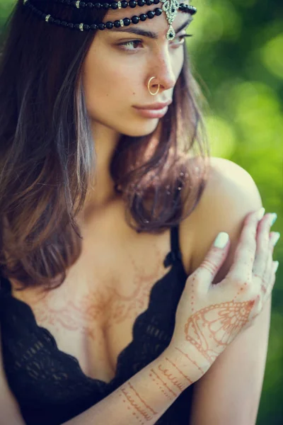 Drawing mehndi by means of henna on hands and a back of the girl