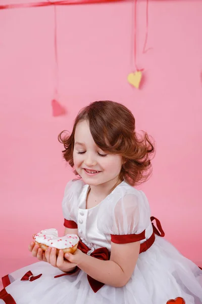 Retrato de uma menina com um donut nas mãos sobre fundo rosa — Fotografia de Stock
