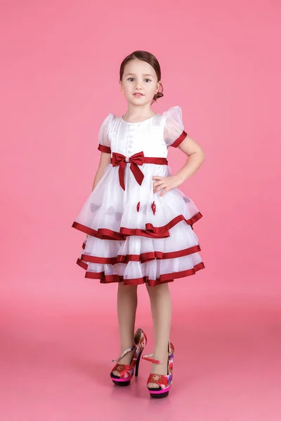 Portrait of cute little girl standing in white dress with donuts or glass heart — Stock Photo, Image