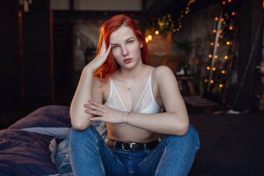 Dinleniyor. Ahşap odada poz katta seksi bir kızıl kız Portresi.