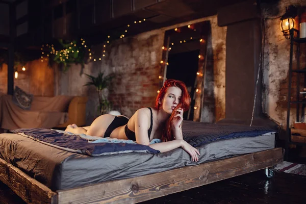 Pihenőidő. Portré egy szexi vöröshajú lány a padlón pózol a fából készült szoba. — Stock Fotó