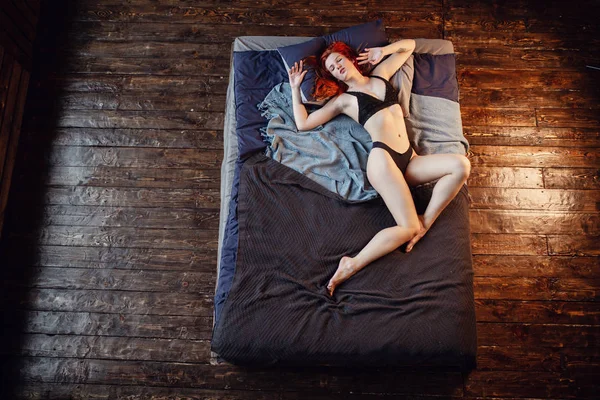 Ausruhen. Porträt eines sexy rothaarigen Mädchens auf dem Boden, das im Holzzimmer posiert. — Stockfoto