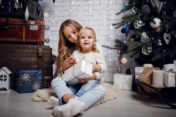 Crianças debaixo da árvore de Natal com caixas de presente. Decorações de Ano Novo . — Fotografia de Stock
