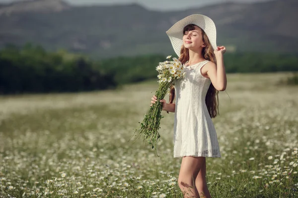 Liten flicka i ett fält av daisy blommor — Stockfoto