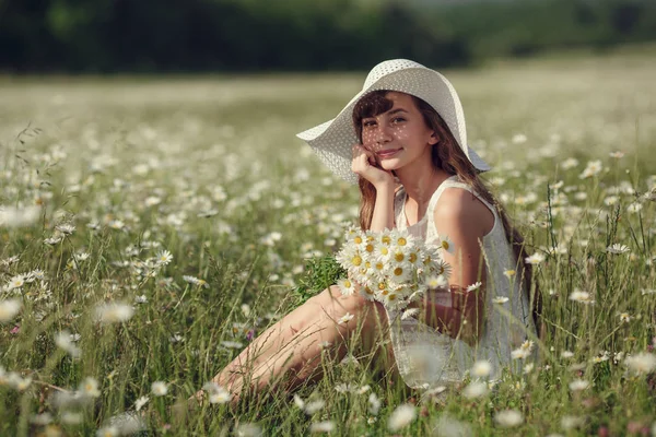 Liten flicka i ett fält av daisy blommor — Stockfoto