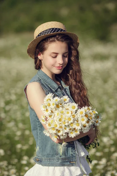 Liten flicka i ett fält av daisy blommor — Stockfoto