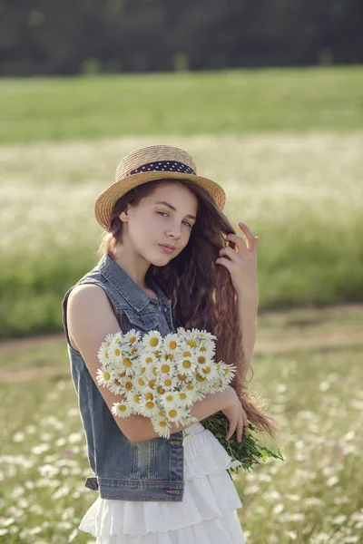 Liten flicka i ett fält av daisy blommor — Stockfoto