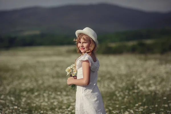 Liten flicka i ett fält av daisy blommor — Stockfoto