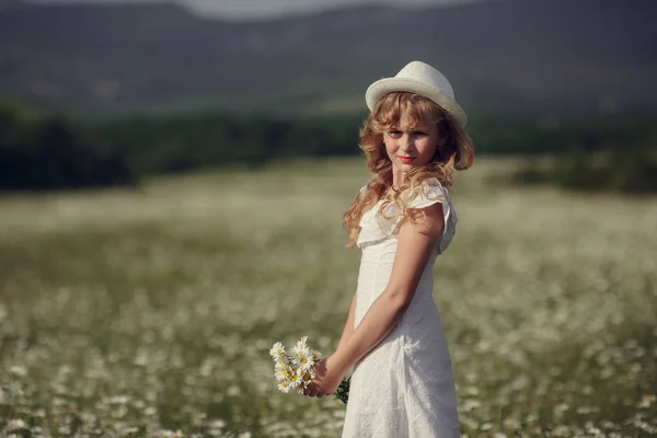 Malá holčička v poli s květinami — Stock fotografie