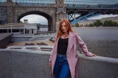 Şehir parkında yürüyen güzel kızıl saçlı kadının portresi.