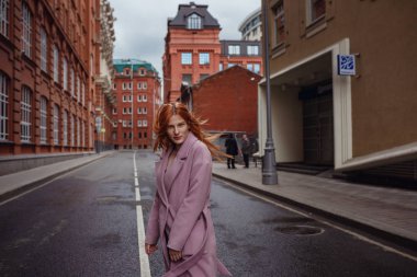 Şehir parkında yürüyen güzel kızıl saçlı kadının portresi.