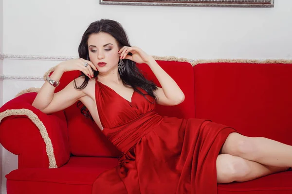Den vackra flickan i en lång röd klänning poserar — Stockfoto