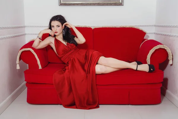 Den vackra flickan i en lång röd klänning poserar — Stockfoto