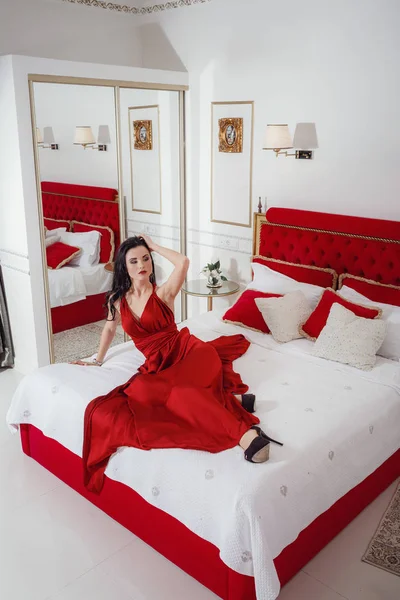 Lockande kvinna i röd klänning avkopplande på en soffa i lyxiga interiören — Stockfoto